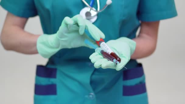 Лікар медсестра жінка носить захисну маску і латексні рукавички - тримає пробірку крові і шприц — стокове відео