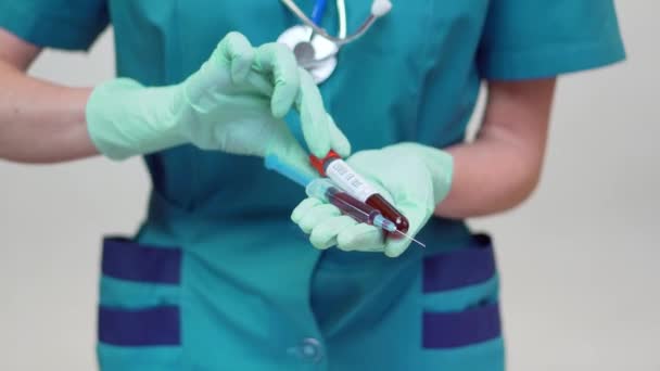 Dokter verpleegkundige vrouw dragen beschermende masker en latex handschoenen - Holding bloed reageerbuis en spuit — Stockvideo