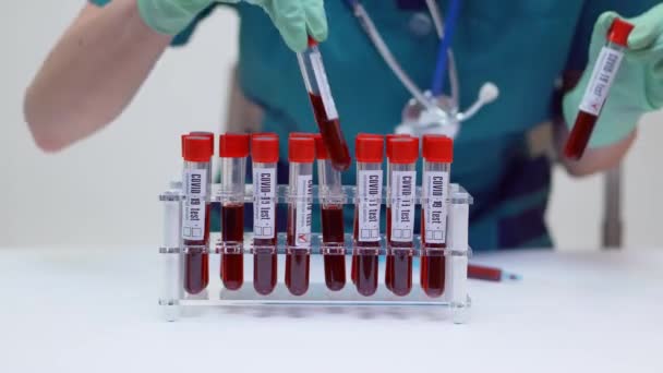 Koruyucu maskeli ve lateks eldivenli Doktor Hemşire Kadın Kan Test Tüp Raftında çalışıyor — Stok video