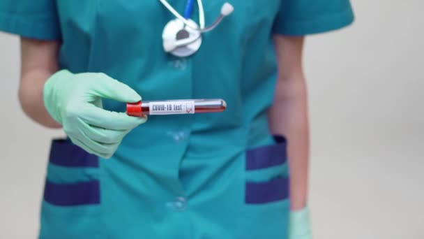 Médico enfermera mujer con máscara protectora y guantes de látex - sosteniendo el tubo de análisis de sangre — Vídeo de stock