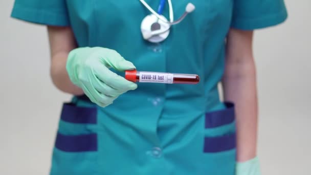 Läkare sjuksköterska kvinna bär skyddande mask och latexhandskar - håller blodprovsrör — Stockvideo