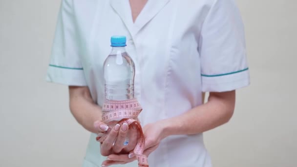 Концепция здорового образа жизни врача-диетолога - держать бутылку воды и измерительную ленту — стоковое видео