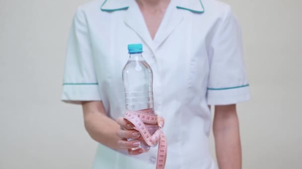 Nutriční lékař zdravý životní styl koncept - držení láhve vody a měřicí pásky — Stock video