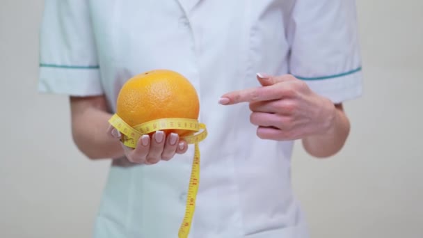 Nutricionista médico conceito de estilo de vida saudável - segurando frutas laranja e fita métrica — Vídeo de Stock