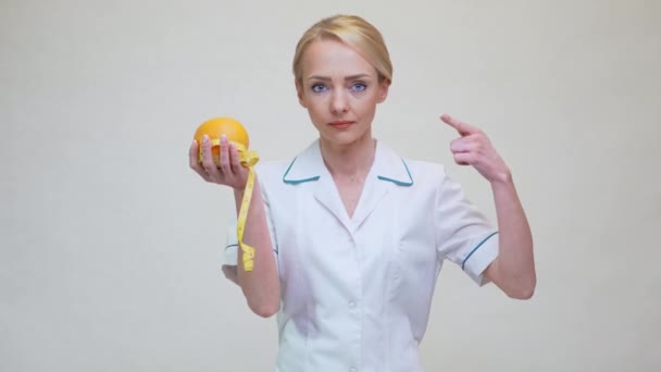 Nutritionist doctor healthy lifestyle concept - holding orange fruit and measuring tape — Stock Video