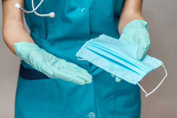 Médico enfermera mujer con estetoscopio sobre fondo gris claro - mostrando máscara protectora — Foto de Stock