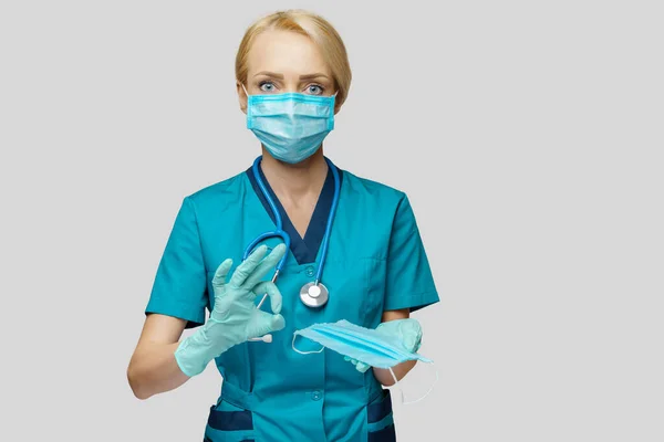 Лікар медсестра жінка зі стетоскопом на світло-сірому фоні - показує захисну маску — стокове фото