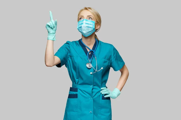 보호용 마스크와 라텍스 장갑을 끼고 있는 의사 간호사 - 빈 모방 공간에 손가락을 치켜들고 있다 — 스톡 사진