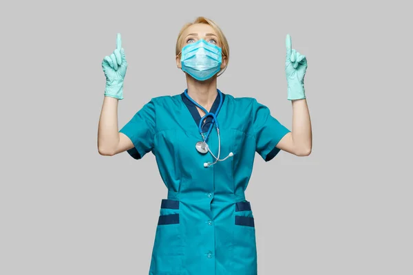 Lekarz pielęgniarka kobieta w masce ochronnej i rękawiczki lateksowe - wskazać palcem w pustej przestrzeni copyspace — Zdjęcie stockowe