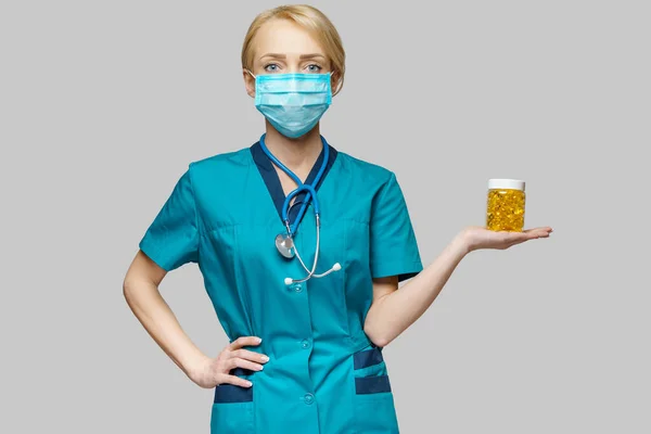 Medical doctor nurse woman wearing protective mask and rubber or latex gloves - holding can of pills — Stock Photo, Image