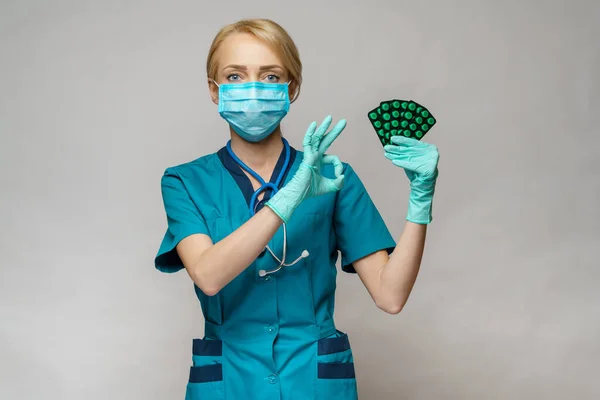 Médico enfermera mujer con máscara protectora y guantes de goma o látex - que contiene ampollas de píldoras — Foto de Stock