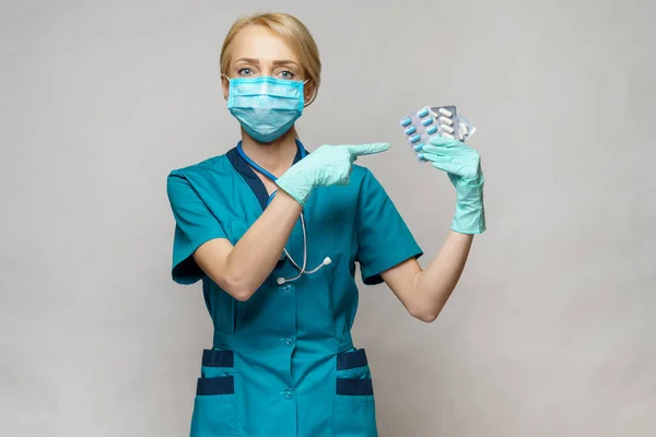 Médico enfermera mujer con máscara protectora y guantes de goma o látex - que contiene ampollas de píldoras — Foto de Stock