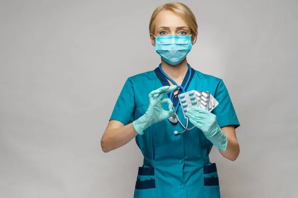 Zdravotní sestra žena v ochranné masce a gumové nebo latexové rukavice - drží puchýře pilulek — Stock fotografie