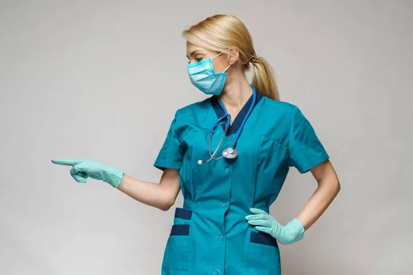 Médecin infirmière femme portant un masque de protection et des gants en latex - montrant sur la liste virtuelle — Photo