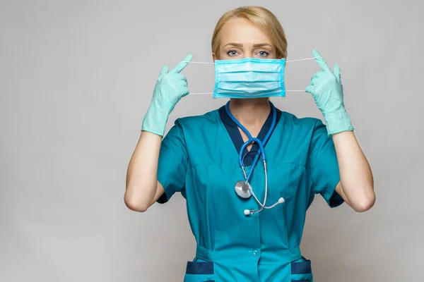 Médico enfermera mujer con estetoscopio sobre fondo gris claro - mostrando máscara protectora —  Fotos de Stock