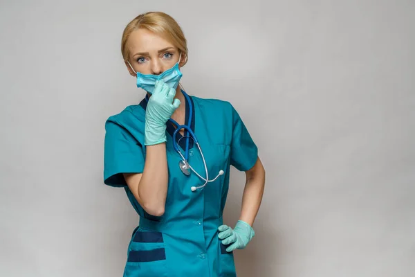 Médico enfermera mujer con máscara protectora y guantes de goma o látex - cansado y estresado — Foto de Stock