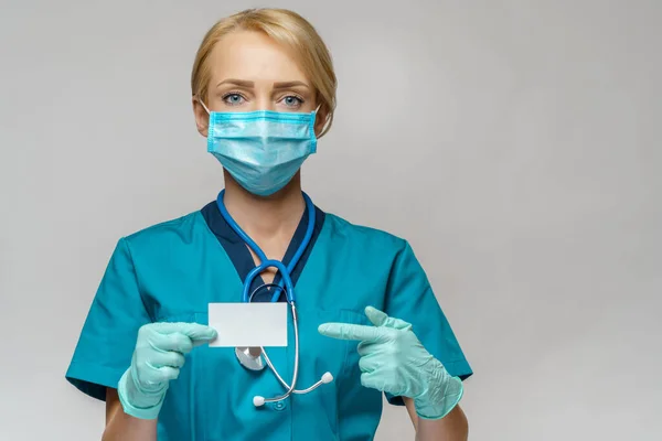 Médico enfermera mujer con máscara protectora y guantes - mostrando la tarjeta de visita en blanco —  Fotos de Stock