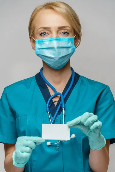 Médico enfermera mujer con máscara protectora y guantes - mostrando la tarjeta de visita en blanco —  Fotos de Stock