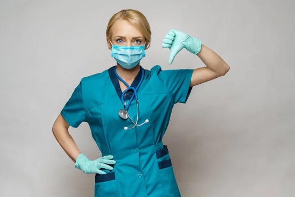 Enfermera médica mujer con máscara protectora y guantes de látex - mostrando el pulgar grande hacia abajo — Foto de Stock