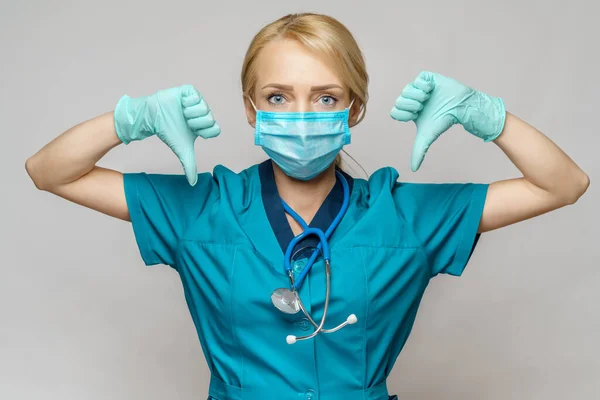 Врач медсестра женщина в защитной маске и латексных перчатках - показывая большой палец вниз — стоковое фото