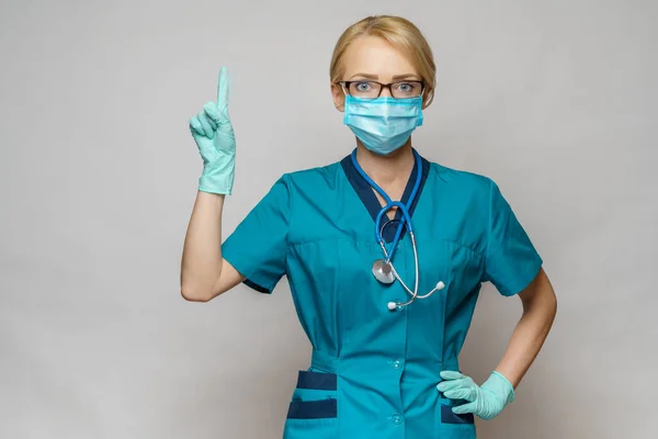 Врач медсестра женщина в защитной маске и латексных перчатках - укажите пальцем на пустое копировальное пространство — стоковое фото