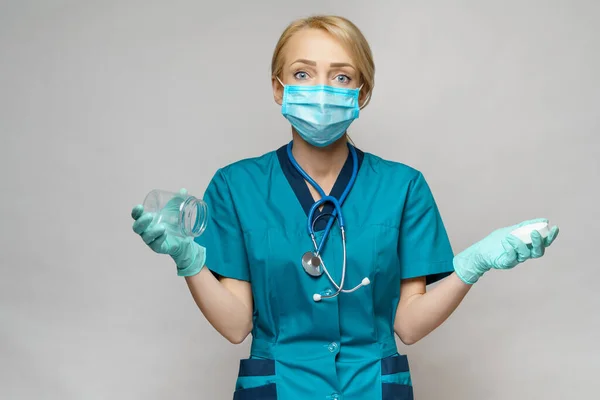 Médico enfermera mujer con máscara protectora y guantes - sosteniendo lata vacía o frasco de píldoras — Foto de Stock