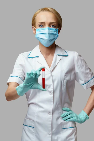 Ιατρός νοσοκόμα γυναίκα φορώντας προστατευτική μάσκα και γάντια - κρατώντας εξέταση αίματος ιού — Φωτογραφία Αρχείου