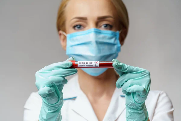 保護マスクと手袋を身に着けている医療看護師の女性-ウイルスの血液検査を保持 — ストック写真