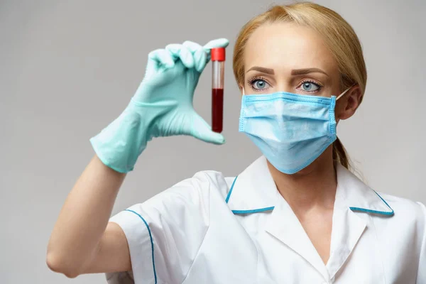 Ärztin Krankenschwester mit Schutzmaske und Handschuhen - hält Virusbluttest — Stockfoto