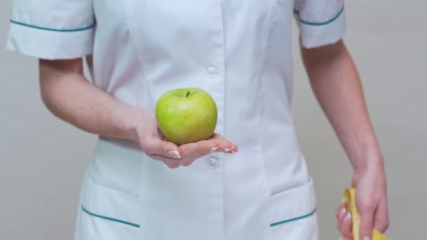 Nutricionista médico concepto de estilo de vida saludable - la celebración de manzana verde orgánica y cinta métrica — Vídeos de Stock