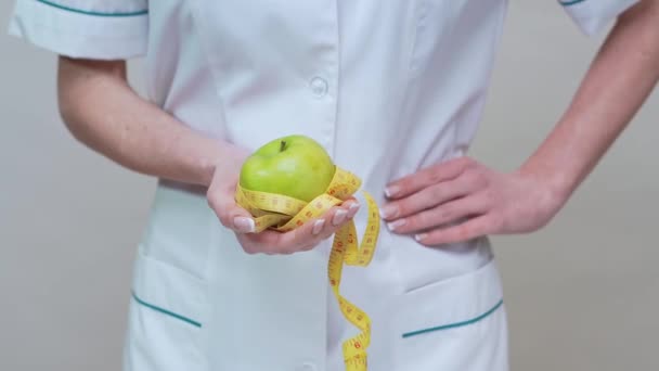 Nutricionista médico concepto de estilo de vida saludable - la celebración de manzana verde orgánica y cinta métrica — Vídeos de Stock