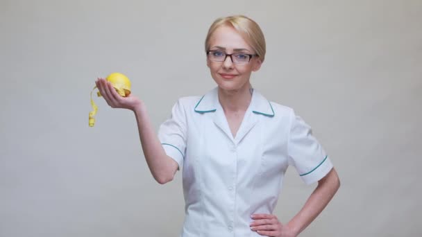 Nutritionist doctor healthy lifestyle concept - holding organic lemon fruit and measurng tape — Stock Video