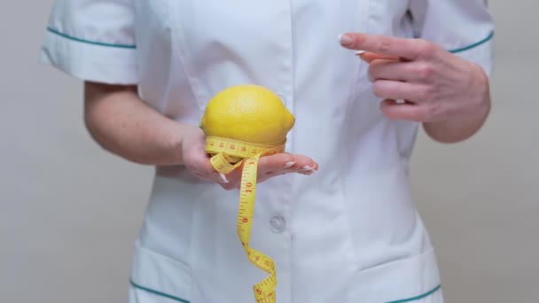 Nutricionista médico conceito de estilo de vida saudável - segurando frutas de limão orgânicos e fita métrica — Vídeo de Stock