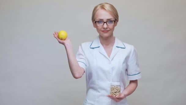 Nutritionist doctor healthy lifestyle concept - holding organic lemon fruit and jar of vitamin pills — Stock Video