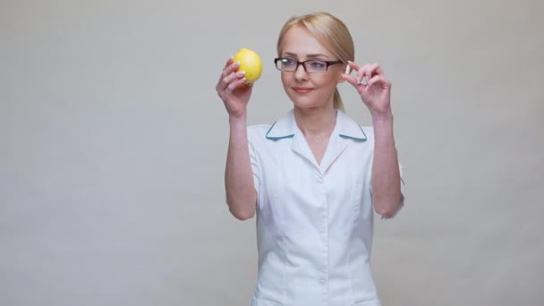 Nutritionist doctor healthy lifestyle concept - holding lemon fruit and medicine or vitamin pill — Stock Video