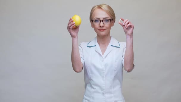 Nutritionist doctor healthy lifestyle concept - holding lemon fruit and medicine or vitamin pill — Stock Video