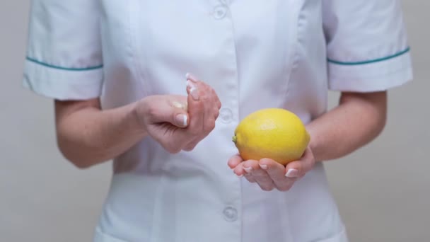Nutricionista médico concepto de estilo de vida saludable - celebración de frutas de limón y medicamentos o píldoras vitamínicas — Vídeo de stock
