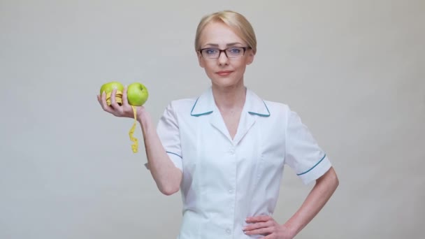 Nutritionist doctor healthy lifestyle concept - holding two organic green apples and measuring tape — Stock Video