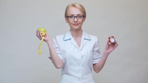 Концепция здорового образа жизни врача-диетолога - зеленое яблоко, будильник и измерительная лента — стоковое видео