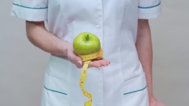 Concepto de estilo de vida saludable médico nutricionista - la celebración de manzana verde, despertador y cinta métrica — Vídeos de Stock