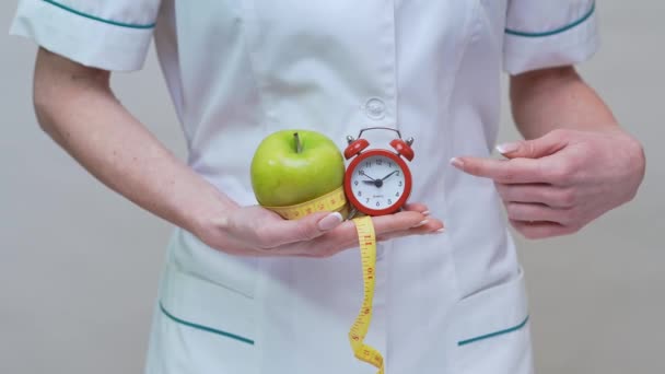 Concepto de estilo de vida saludable médico nutricionista - la celebración de manzana verde, despertador y cinta métrica — Vídeos de Stock