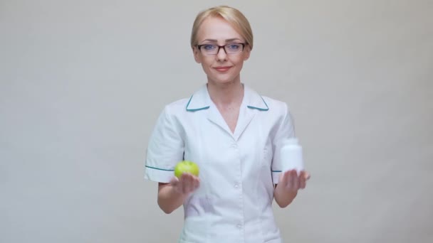 Nutritionist läkare hälsosam livsstil koncept - hålla ekologisk grönt äpple och burk med vitaminpiller — Stockvideo