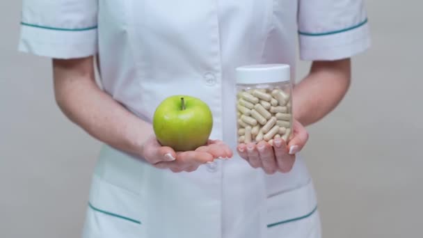 Nutricionista médico concepto de estilo de vida saludable - la celebración de manzana verde orgánica y frasco de píldoras vitamínicas — Vídeos de Stock