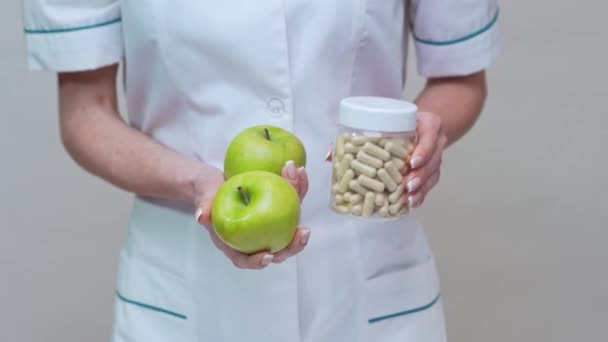 Nutricionista médico concepto de estilo de vida saludable - la celebración de manzana verde orgánica y frasco de píldoras vitamínicas — Vídeo de stock