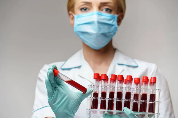 Médico enfermera mujer con máscara protectora y guantes - cremallera con análisis de sangre de virus —  Fotos de Stock