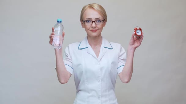 Nutritionist doctor healthy lifestyle concept - holding bottle of water and red alarm clock — Stock Video