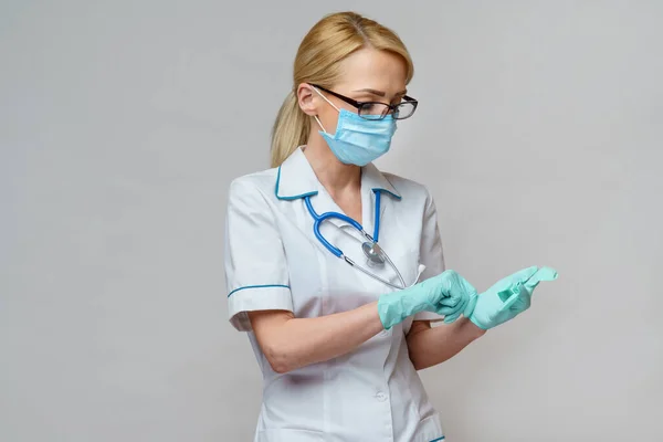 Médico enfermera mujer con estetoscopio con máscara protectora y guantes de látex de goma —  Fotos de Stock