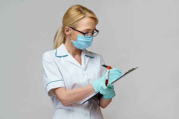 Medische arts verpleegkundige vrouw met beschermende masker en handschoenen - houden virus bloedonderzoek en vliegtuig tafel — Stockfoto