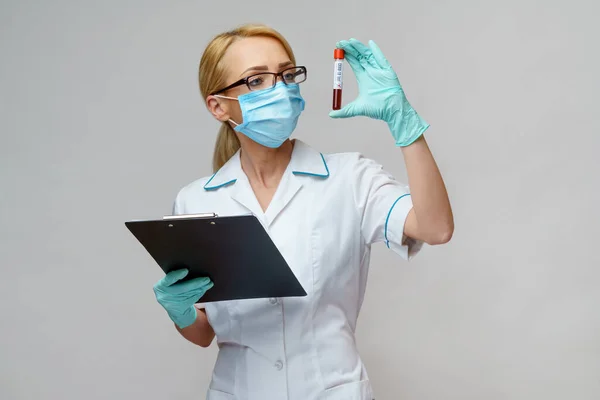 Medische arts verpleegkundige vrouw met beschermende masker en handschoenen - houden virus bloedonderzoek en vliegtuig tafel — Stockfoto