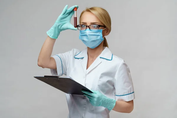 Médico enfermera mujer con máscara protectora y guantes - la celebración de análisis de sangre del virus y la mesa de avión —  Fotos de Stock